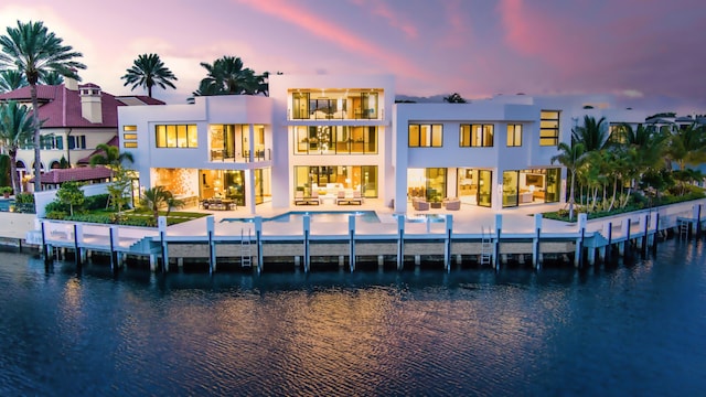 back of property featuring stucco siding, a water view, a balcony, and a patio area