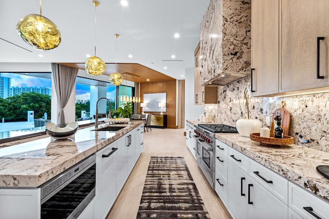 kitchen with white cabinetry, an island with sink, range with two ovens, and sink