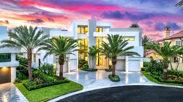 contemporary house featuring a balcony, decorative driveway, and stucco siding