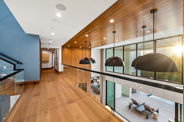 corridor featuring wood walls and light hardwood / wood-style flooring