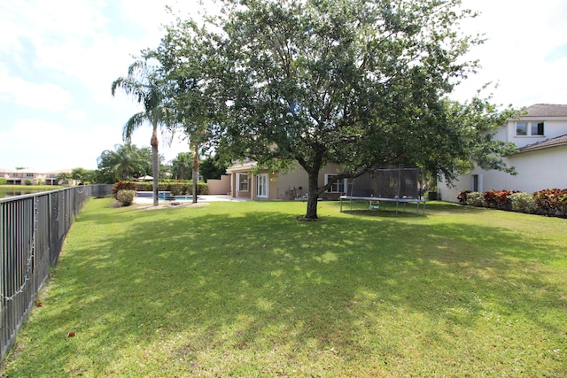 view of yard featuring a trampoline and a fenced in pool