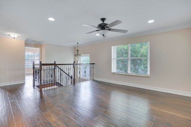 empty room featuring ornamental molding, a healthy amount of sunlight, and dark hardwood / wood-style flooring