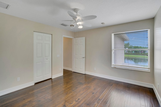 unfurnished bedroom with a closet, ceiling fan, and dark wood-type flooring