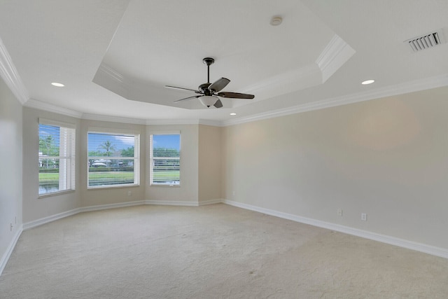 unfurnished room with light colored carpet, a raised ceiling, ceiling fan, and crown molding