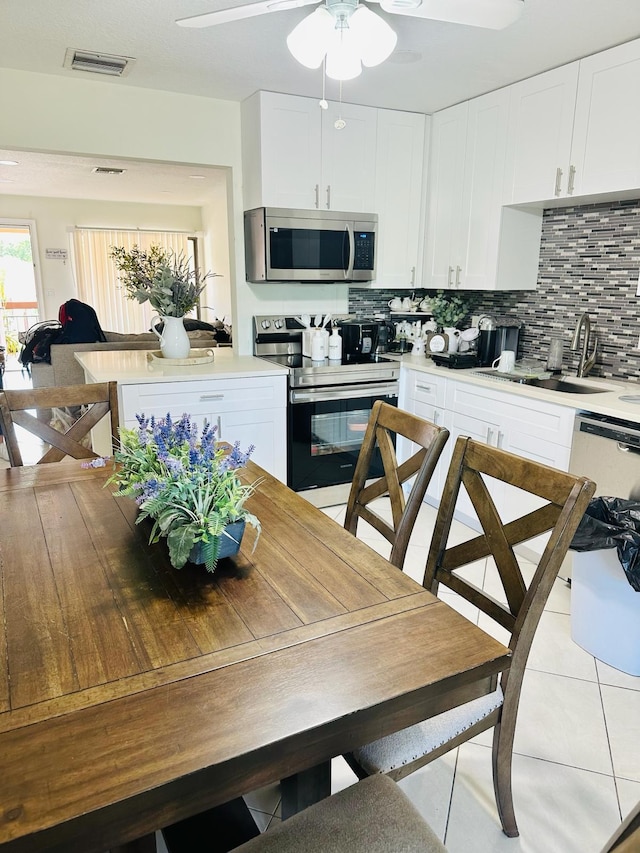 kitchen featuring white cabinets, sink, light tile patterned floors, appliances with stainless steel finishes, and tasteful backsplash