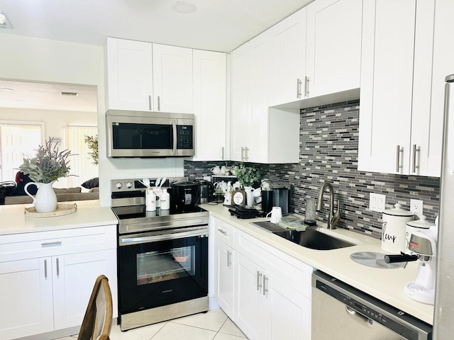 kitchen with tasteful backsplash, white cabinetry, sink, and appliances with stainless steel finishes