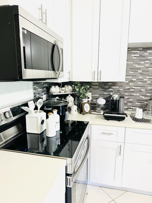 kitchen featuring white electric range oven, decorative backsplash, white cabinetry, and light tile patterned floors