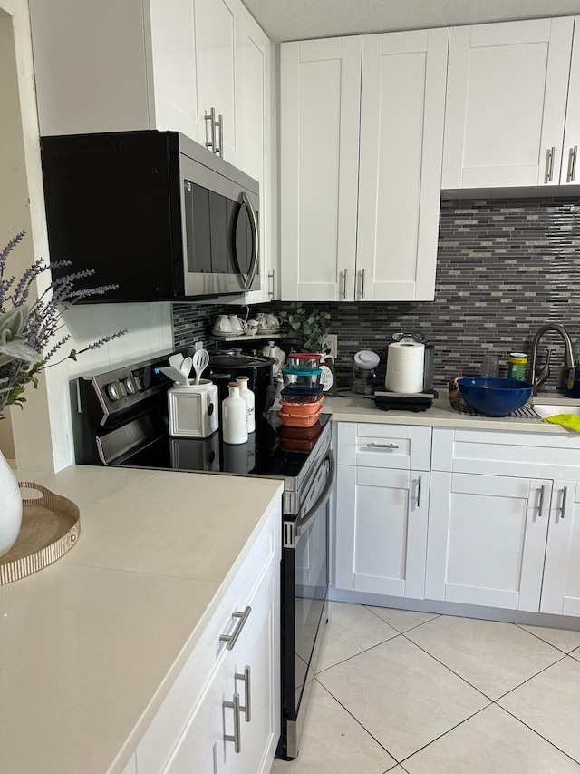 kitchen with white cabinets, backsplash, light tile patterned floors, and stainless steel appliances