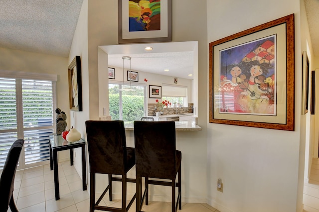 tiled dining room featuring sink, a textured ceiling, and a wealth of natural light