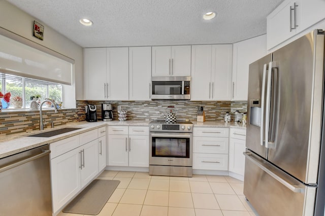 kitchen with backsplash, appliances with stainless steel finishes, light tile floors, and sink