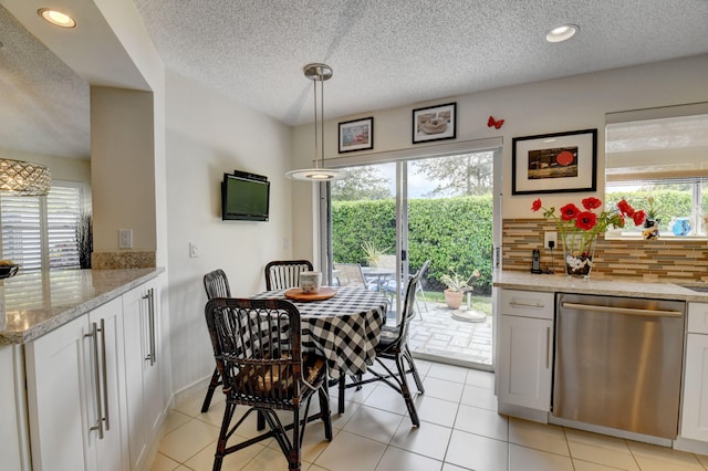 tiled dining area with a textured ceiling and a healthy amount of sunlight