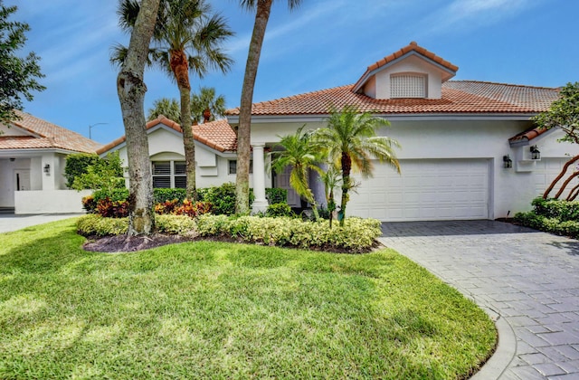 mediterranean / spanish home featuring a front lawn and a garage