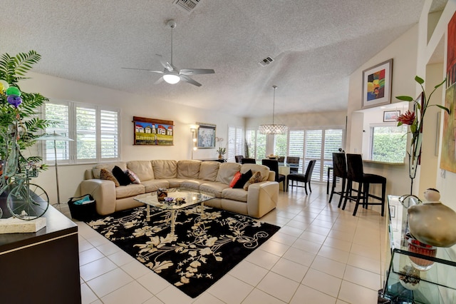 tiled living room featuring lofted ceiling, a textured ceiling, and ceiling fan with notable chandelier