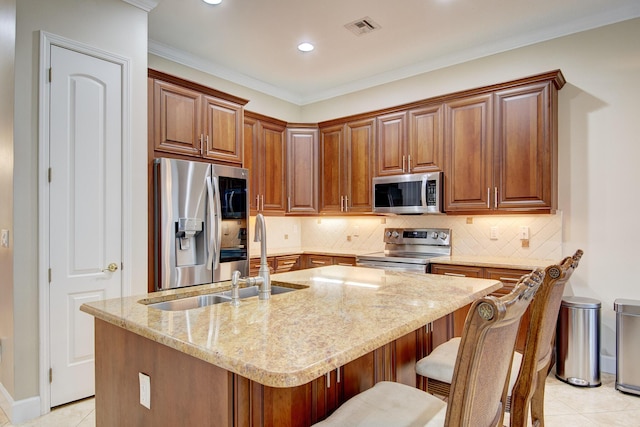 kitchen featuring a kitchen breakfast bar, a center island with sink, light tile patterned floors, and stainless steel appliances