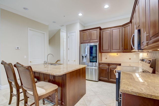 kitchen featuring light stone countertops, appliances with stainless steel finishes, sink, light tile patterned floors, and an island with sink