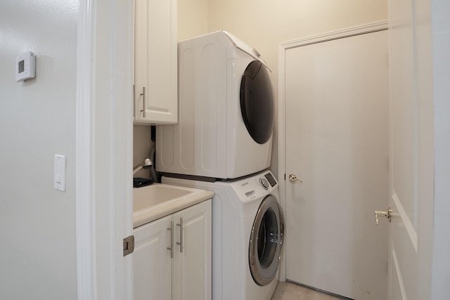 washroom featuring cabinets and stacked washer / dryer