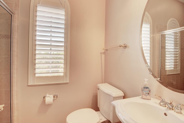 bathroom featuring an enclosed shower, toilet, and sink