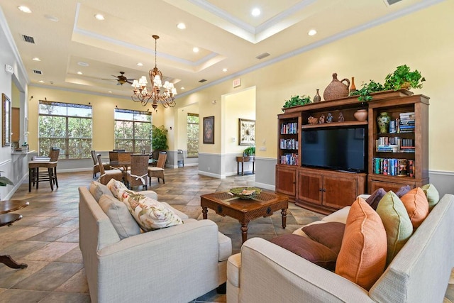 living room with a tray ceiling, crown molding, and ceiling fan with notable chandelier