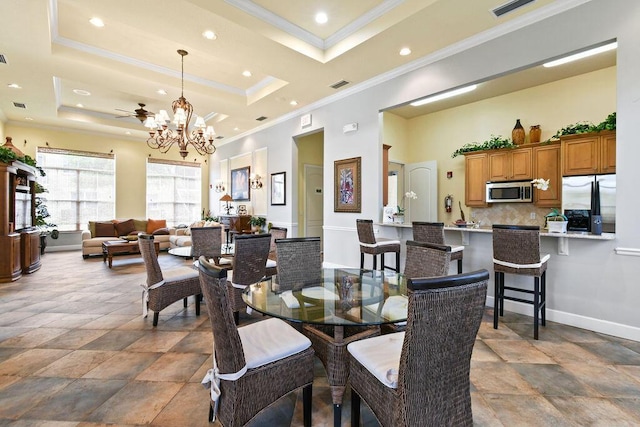 dining area with ceiling fan with notable chandelier, a raised ceiling, crown molding, and a high ceiling