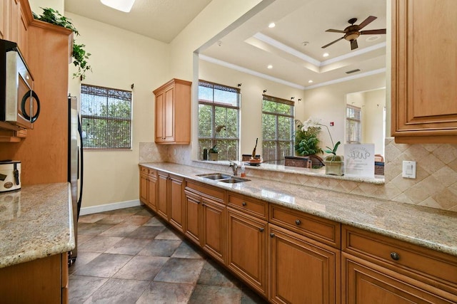 kitchen featuring ceiling fan, light stone counters, and sink