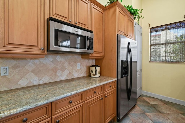 kitchen with light stone counters, stainless steel appliances, and tasteful backsplash