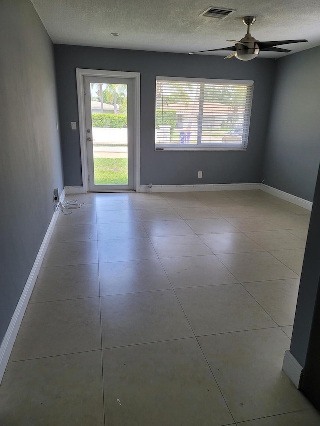 tiled empty room featuring ceiling fan and a textured ceiling