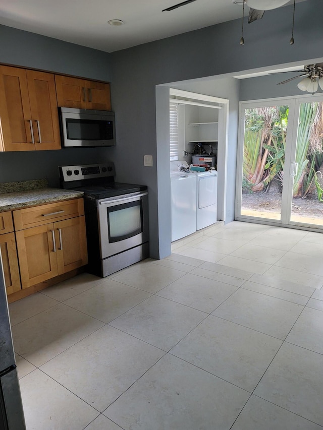 kitchen with appliances with stainless steel finishes, washer and dryer, ceiling fan, and light tile floors