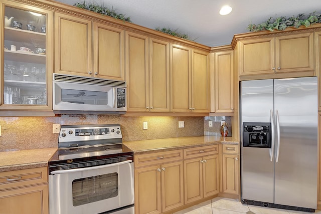 kitchen with backsplash, light tile patterned flooring, and stainless steel appliances