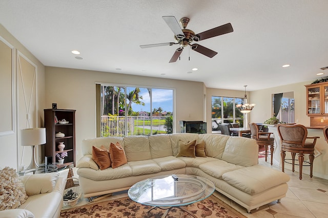 living room with plenty of natural light, light tile patterned floors, and ceiling fan with notable chandelier