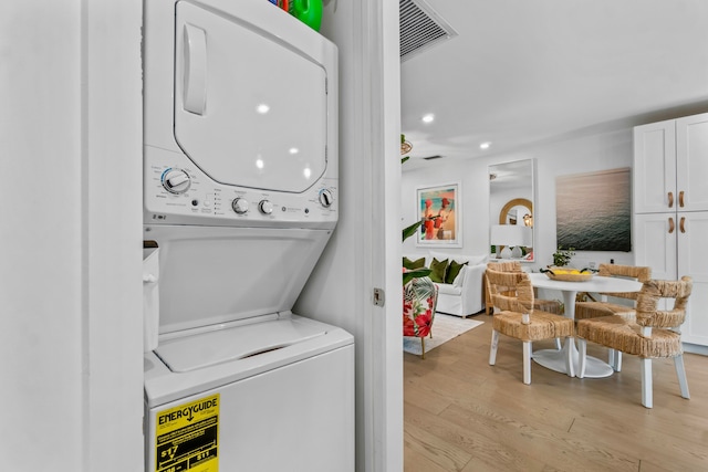 laundry room featuring stacked washer and clothes dryer and light hardwood / wood-style floors