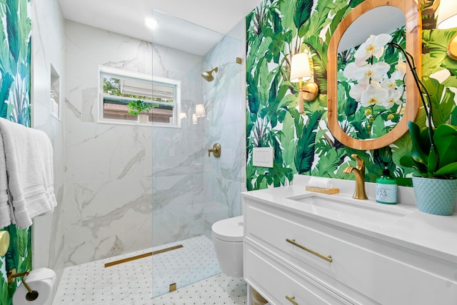 bathroom with toilet, tiled shower, and vanity with extensive cabinet space