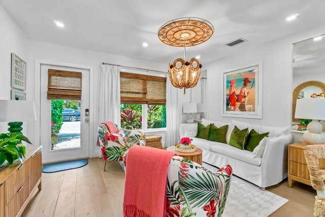 living room with a healthy amount of sunlight, light wood-type flooring, and a notable chandelier