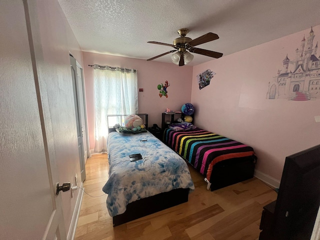 bedroom with ceiling fan, light hardwood / wood-style floors, and a textured ceiling