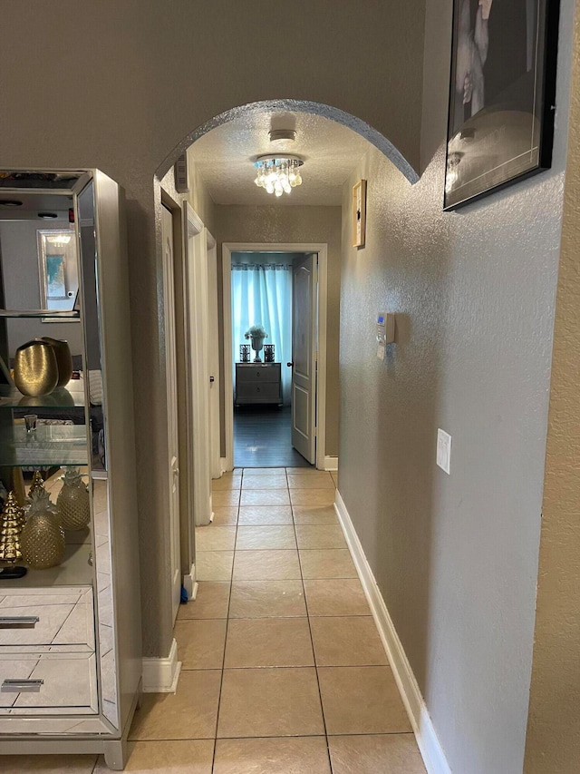 hallway featuring light tile floors and a textured ceiling