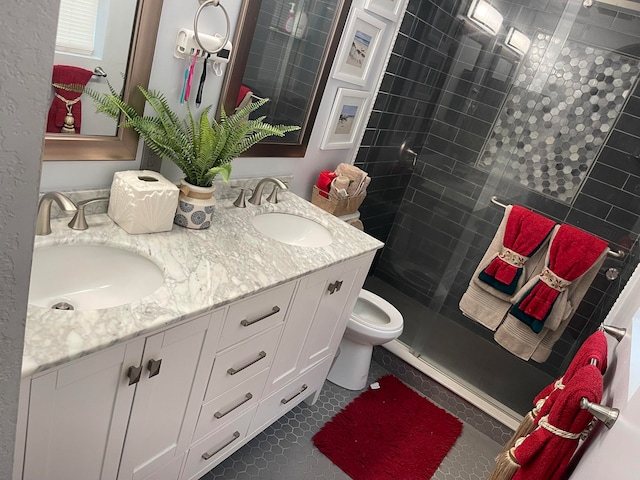 bathroom with a shower with shower door, toilet, double vanity, and tile floors