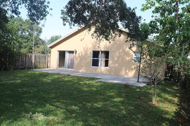 rear view of house with a patio and a lawn