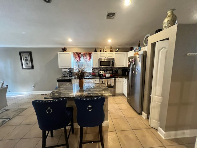 kitchen with dark stone counters, tasteful backsplash, stainless steel appliances, light tile floors, and white cabinetry