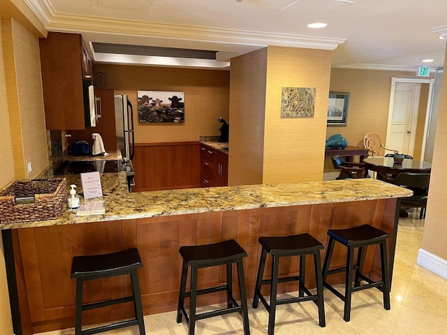 bar featuring stainless steel refrigerator, crown molding, light stone countertops, and wood walls