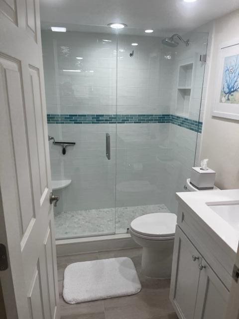 bathroom with vanity, a shower with shower door, and toilet