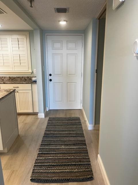 doorway to outside featuring light hardwood / wood-style floors and a textured ceiling