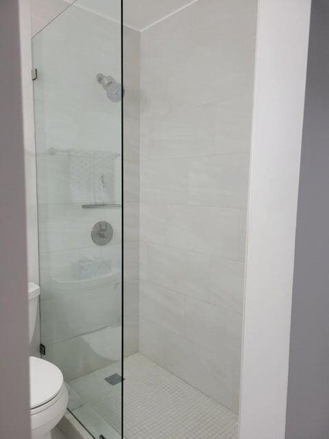 bathroom with tiled shower and toilet