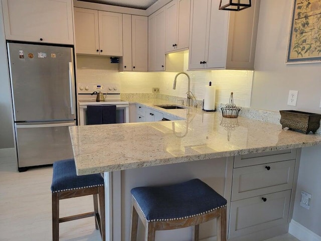 kitchen with stainless steel fridge, electric range oven, a kitchen breakfast bar, and sink