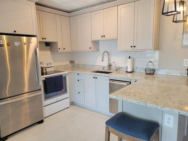 kitchen featuring a kitchen breakfast bar, sink, hanging light fixtures, light stone counters, and stainless steel appliances