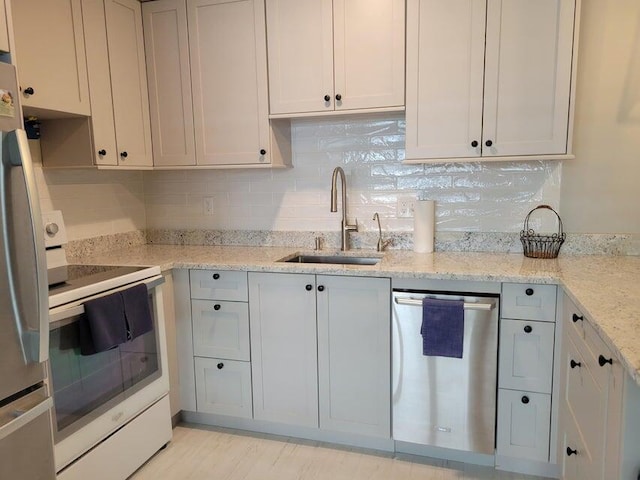 kitchen with light stone countertops, decorative backsplash, stainless steel appliances, sink, and white cabinets