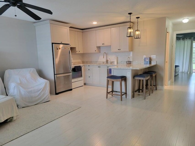 kitchen featuring stainless steel refrigerator, kitchen peninsula, white cabinets, and a breakfast bar area