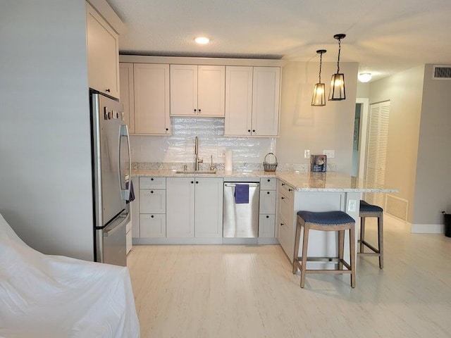 kitchen featuring kitchen peninsula, a kitchen breakfast bar, stainless steel appliances, sink, and white cabinets