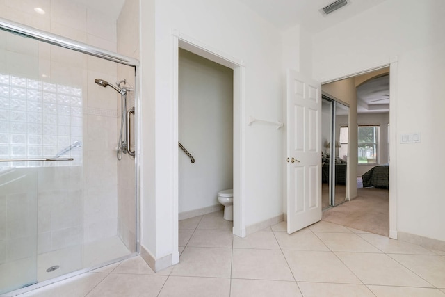 bathroom featuring tile patterned floors, toilet, and a shower with shower door