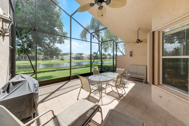 sunroom / solarium featuring ceiling fan and a water view