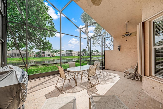 sunroom with ceiling fan and a water view