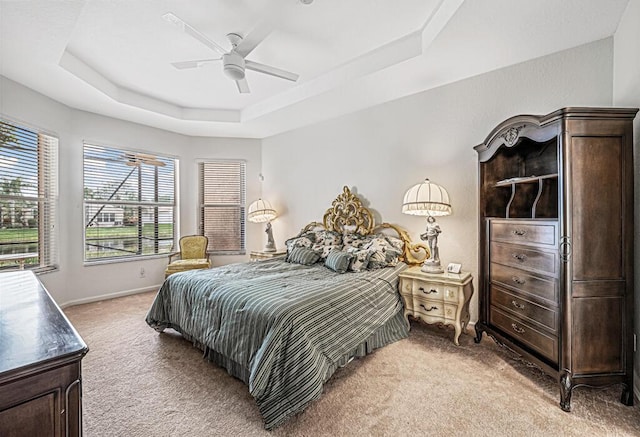 carpeted bedroom featuring ceiling fan and a raised ceiling